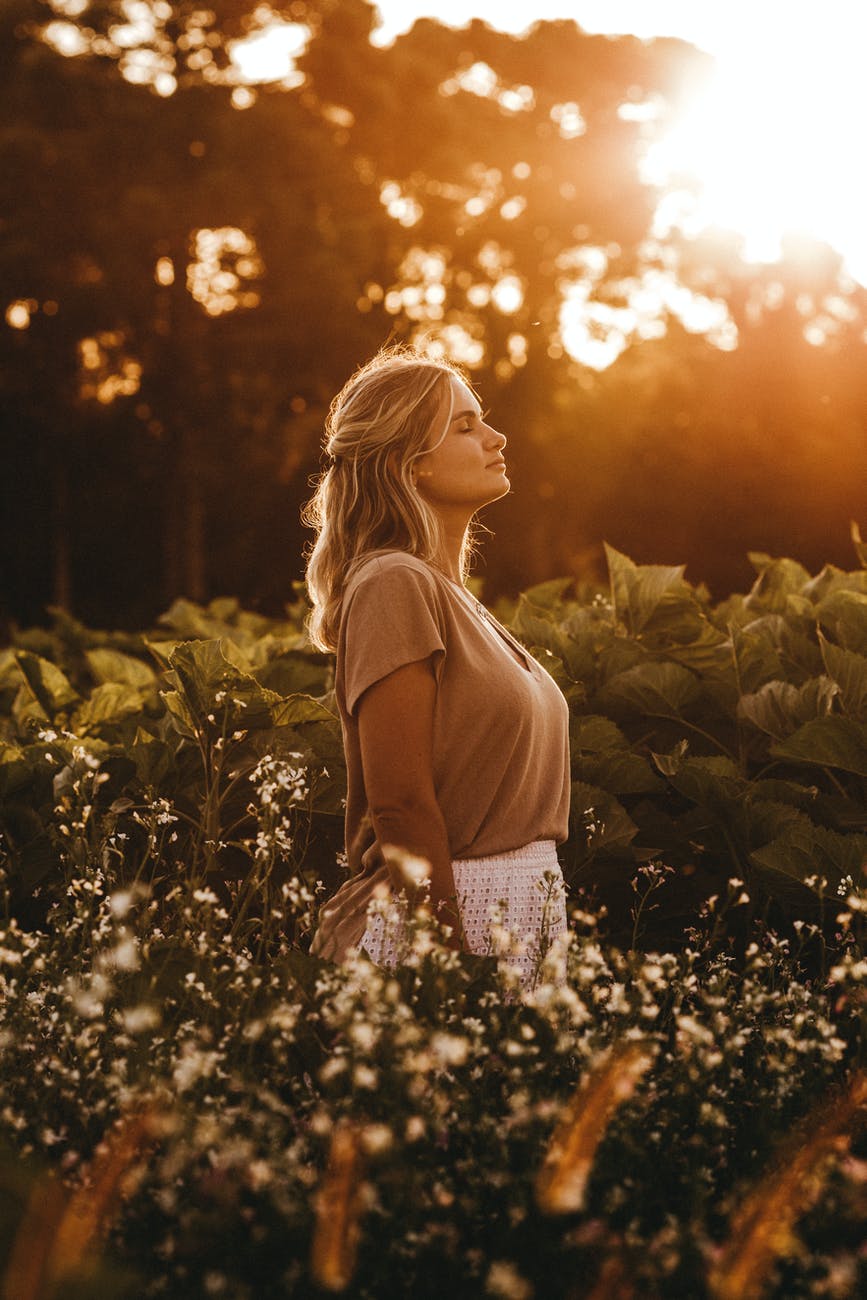 dreamy woman standing on lush field at sunset