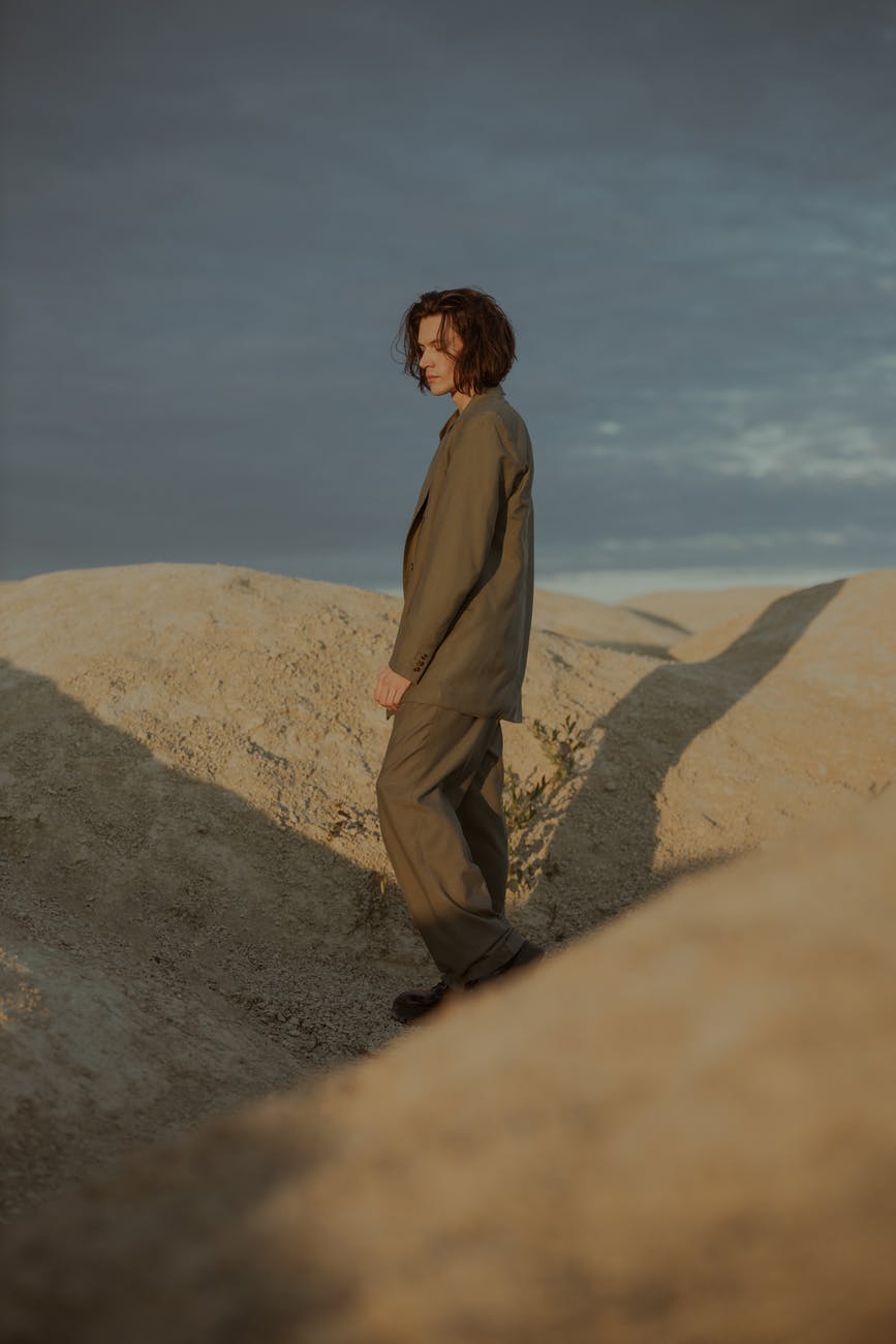 man in brown coat standing on brown sand