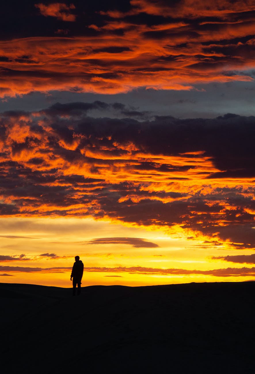person standing in distance against beautiful vibrant sunset