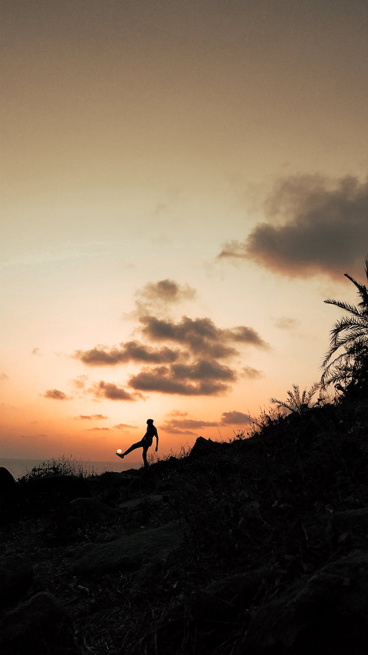 anonymous person kicking sun under sunset sky