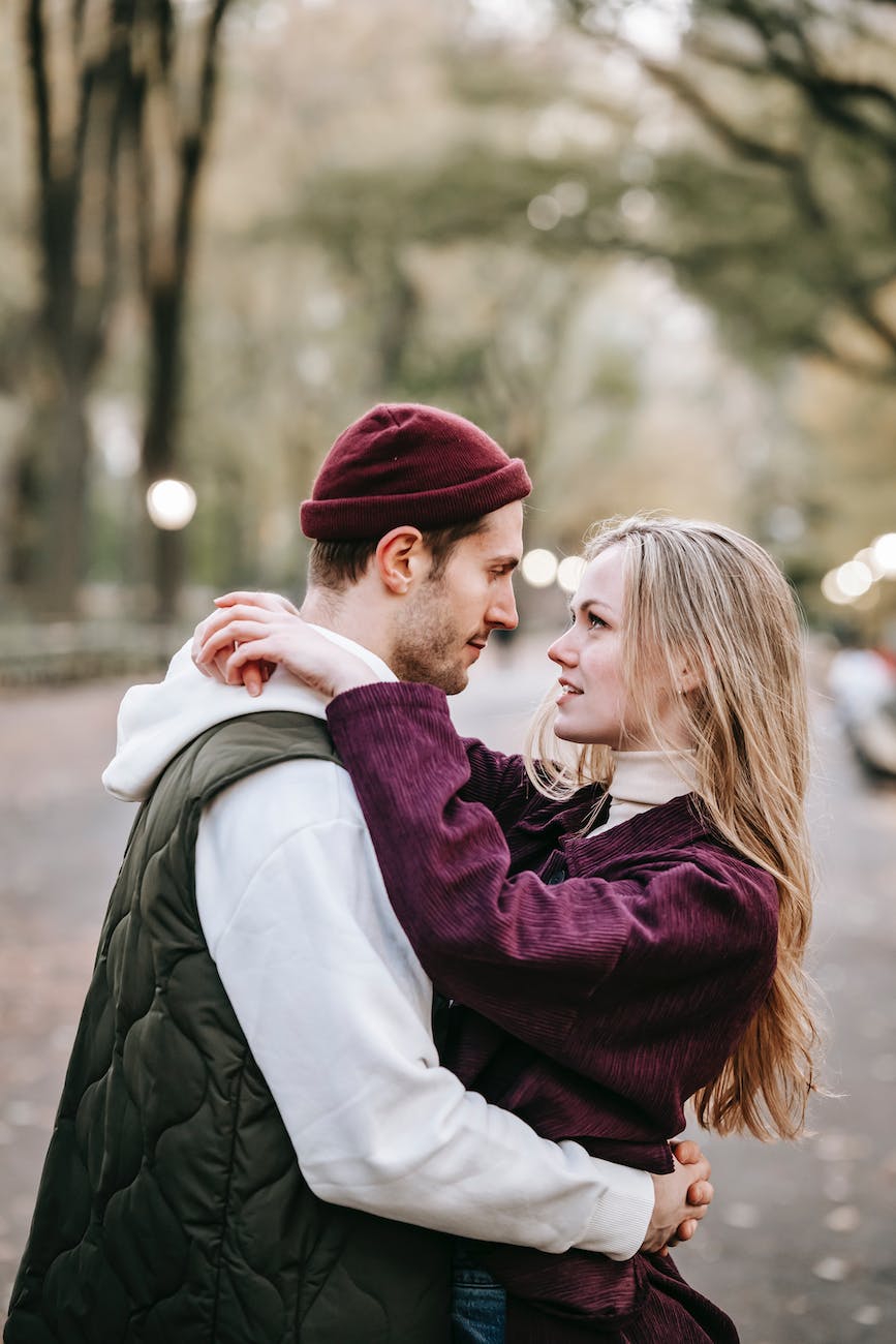 couple standing in street while hugging near trees