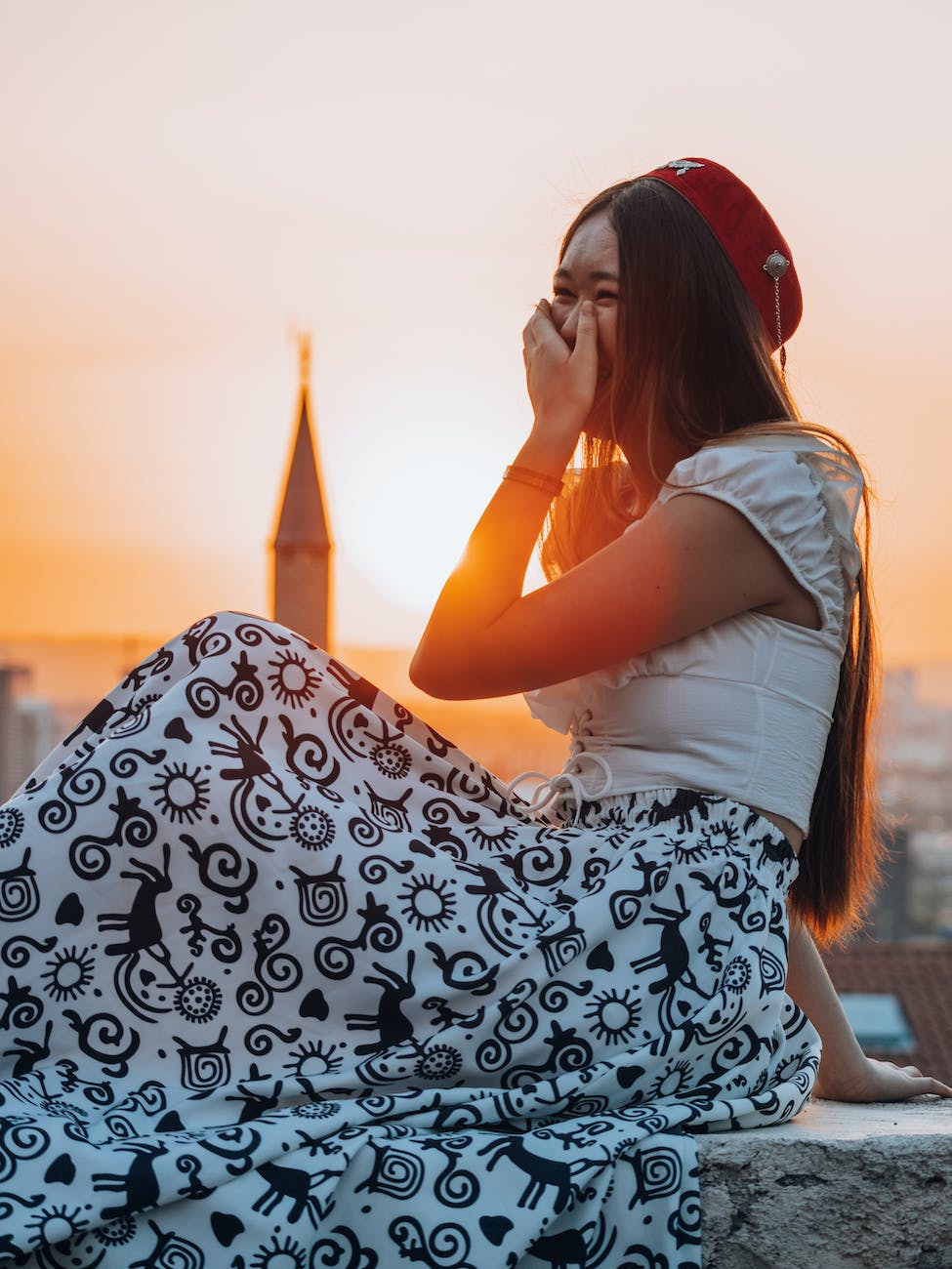 young woman sitting on the wall at sunset